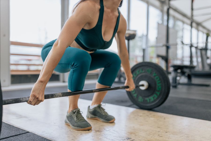 A lifter setting up under a loaded barbell on a gym floor